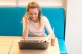 Portrait of beautiful smiling woman sitting on a comfortable chair in a cafe with black laptop. Pretty student doing work with lap Royalty Free Stock Photo