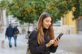 Portrait of a beautiful smiling woman using a mobile phone in city street with tangerine trees Royalty Free Stock Photo