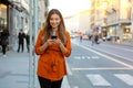 Portrait of beautiful smiling woman walking in city street texting on mobile phone with blurred background Royalty Free Stock Photo