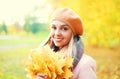 Portrait beautiful smiling woman with yellow maple leafs in warm sunny autumn Royalty Free Stock Photo