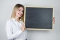 Portrait of a beautiful smiling young blonde woman holding a blank whiteboard at the height of her face, with room to add text clo Royalty Free Stock Photo