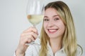 Portrait of a beautiful smiling young blonde woman who raises a glass of white wine to show its color and nuances Royalty Free Stock Photo