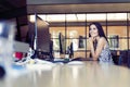 Portrait of beautiful smiling young brunette businesswoman sitting at bright modern work station and typing on computer Royalty Free Stock Photo