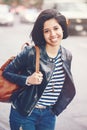 Portrait of beautiful smiling young Caucasian latin girl woman with dark brown eyes, short dark hair, in blue jeans, leather biker Royalty Free Stock Photo