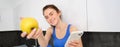 Portrait of beautiful, smiling young fitness woman, offering you an apple, eating healthy snack, holding a fruit Royalty Free Stock Photo