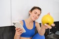 Portrait of beautiful, smiling young fitness woman, offering you an apple, eating healthy snack, holding a fruit Royalty Free Stock Photo