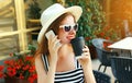 Portrait of beautiful smiling young woman calling on smartphone sitting at a table in a cafe with coffee cup Royalty Free Stock Photo