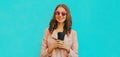 Portrait beautiful smiling young woman with cup of coffee wearing a leather jacket on blue background Royalty Free Stock Photo