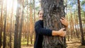 Portrait of beautiful smiling young woman leaning and hugging big old tree in forest. Concept of love, ecology Royalty Free Stock Photo