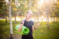 Portrait of a beautiful smiling young woman in a sports uniform with a jump rope and a yoga mat in her hands, posing Royalty Free Stock Photo