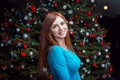 Portrait of beautiful smiling young woman, standing near Christmas tree Royalty Free Stock Photo