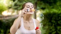 Closeup portrait of beautiful smiling young woman blowing soap bubbles in park at sunset Royalty Free Stock Photo