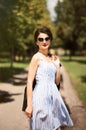 Portrait of beautiful stylish brunette girl in blue and white striped sleeveless dress and sunglasses with black leather jacket in Royalty Free Stock Photo