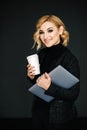 Portrait of a beautiful stylish businesswoman with a laptop and a glass of coffee in her hands and an open friendly smile. The