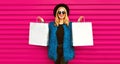 Portrait of beautiful stylish smiling woman with shopping bags wearing blue fur coat, black round hat and sunglasses posing on Royalty Free Stock Photo