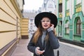 Portrait of a stylish woman listening to music on the background of the beautiful architecture of the old town. Royalty Free Stock Photo