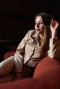 Portrait of beautiful stylish young lady in suit sitting on the red sofa Royalty Free Stock Photo