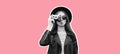 Portrait of beautiful stylish young woman photographer with film camera wearing black round hat, leather jacket isolated on pink Royalty Free Stock Photo