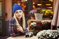Portrait of beautiful stylish young woman sitting in street cafe and drinking coffee. Hipster with old retro camera Royalty Free Stock Photo