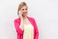 Portrait of beautiful successful young woman in pink blouse standing, using and making call on her smartphone with happy face and Royalty Free Stock Photo