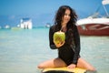 Portrait of a beautiful surfing girl with green coconut from palm tree sit on yellow surf longboard surfboard board. Royalty Free Stock Photo