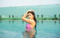 Portrait of beautiful tanned Asian slim woman relaxing and looking at camera in swimming pool spa.Fashionable portrait.Summertime