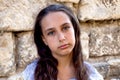 Portrait beautiful tanned caucasian girl against ancient stone wall. Attractive young tourist woman visiting city street Royalty Free Stock Photo