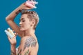 Portrait of beautiful tattooed woman with short hair and closed eyes holding plastic bottles with cosmetic, hair and