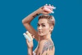 Portrait of beautiful tattooed woman with short hair looking at camera, holding plastic bottles with cosmetic, hair and