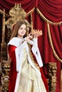 Beautiful teen girl holding crown while sitting in vintage armch Royalty Free Stock Photo