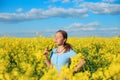 Beautiful teen girl is smiling with yellow flowers in summer field