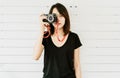 Portrait of beautiful teen girl taking photos with old retro film camera and looking at camera on white wooden wall background. Royalty Free Stock Photo