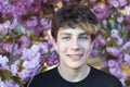 Portrait of a beautiful teenage boy with braces on his teeth against a background of pink flowers Royalty Free Stock Photo
