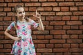 Portrait of a beautiful teenage girl, against a brick wall, the girl raises her finger up, points to an object Royalty Free Stock Photo