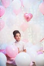 Portrait of a beautiful teenage girl in a lush pink skirt in the scenery of balloons.foil and latex balloons filled with helium