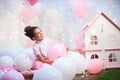 Portrait of a beautiful teenage girl in a lush pink skirt in the scenery of balloons. foil and latex balloons filled with helium.