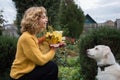 Portrait of a beautiful teenage girl in profile, with bouquet of autumn leaves, playing with white dog Royalty Free Stock Photo