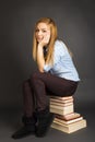 Portrait of beautiful teenage girl sitting on pile of books Royalty Free Stock Photo