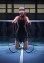 Portrait of a beautiful tennis player posing with two rackets on the court. Sports concept