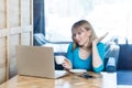 Portrait of beautiful thoughtful young girl with blonde bob haircut hair in blue blouse are sitting in cafe and talking with Royalty Free Stock Photo