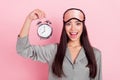 Portrait of beautiful trendy amazed cheerful girl holding wakeup call awake over pink pastel color background