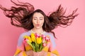Portrait of beautiful trendy dreamy girl holding in hands fresh tulips wind blowing sending air kiss isolated over pink Royalty Free Stock Photo