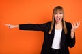 Portrait of beautiful trendy evil furious girl pointing aside creaming rage isolated over bright orange color background