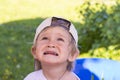 Portrait of a beautiful two year old baby in a baseball cap. A boy with blond hair is carefully looking up somewhere. Royalty Free Stock Photo