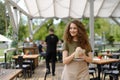 Portrait of a beautiful waitress writing down an order in paper notebook with pen. Server standing on restaurant terrace Royalty Free Stock Photo