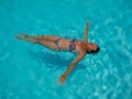 portrait of a beautiful white woman enjoying a relaxing calm time swimming in the transparent water of a pool in a sunny day of