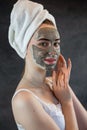 Portrait of beautiful Woman applying nourishing green clay mud mask to her face isolated on black Royalty Free Stock Photo