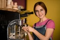 portrait of beautiful woman barista stands at coffee machine and prepares drink