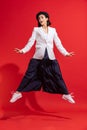 Portrait of beautiful woman in black beret and white jacket posing in a jump isolated over red studio background Royalty Free Stock Photo