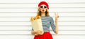 Portrait of beautiful woman blowing her red lips sending sweet air kiss holding grocery shopping paper bag with long white bread Royalty Free Stock Photo